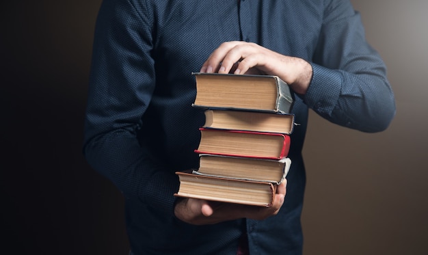 Hombre sujetando libros en sus manos sobre la superficie marrón