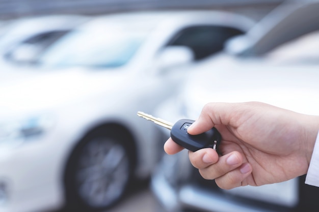 Hombre sujetando la llave del coche y la presiona en el estacionamiento