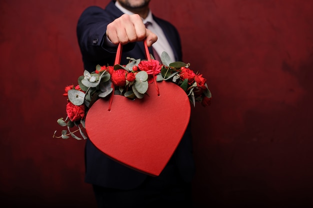 Hombre sujetando en una mano una caja roja de rosas