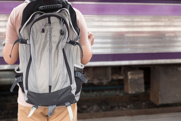 Hombre sujetando el mapa con mochila en la estación de tren