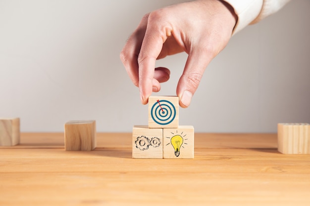 Hombre sujetando metas con idea en cubos de madera