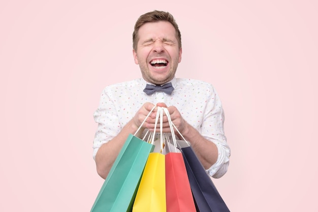 Hombre sujetando montones de bolsas con regalos con shock