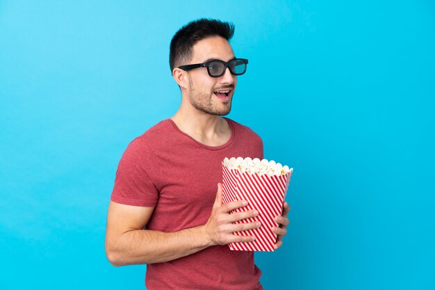 Hombre sujetando una palomitas de maíz sobre pared aislada