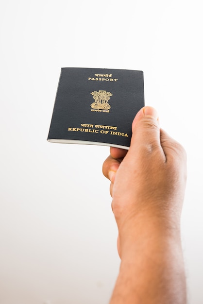 Hombre sujetando pasaporte indio sobre fondo blanco, enfoque selectivo