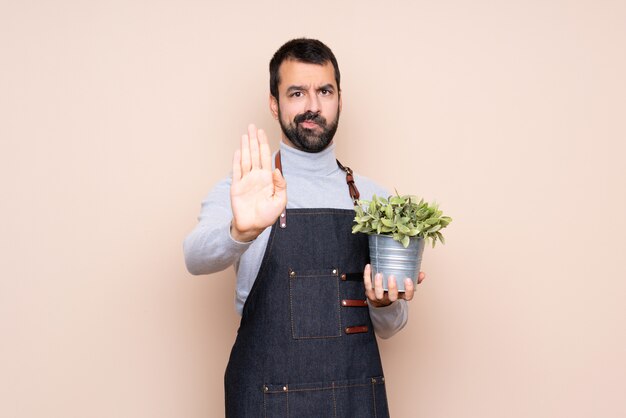 Hombre sujetando una planta haciendo gesto de parada