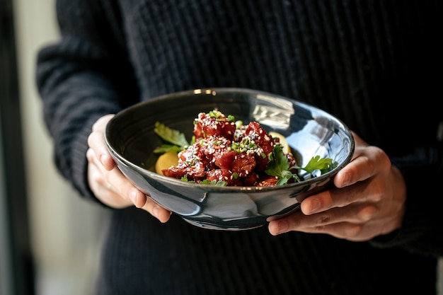 Hombre sujetando un plato de pollo marinado en salsa picante con daikon