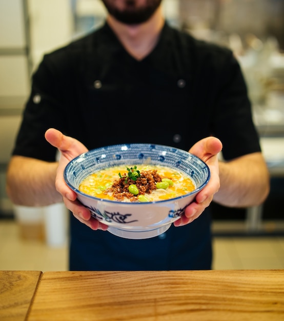 Hombre sujetando un plato de sopa de ramen tantanmen japonesa