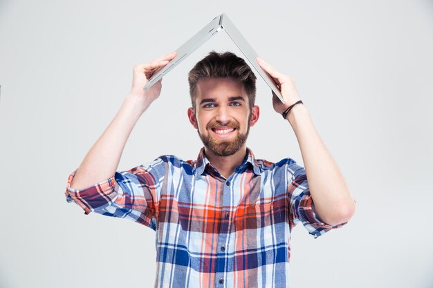 Hombre sujetando el portátil en la cabeza como techo de casa