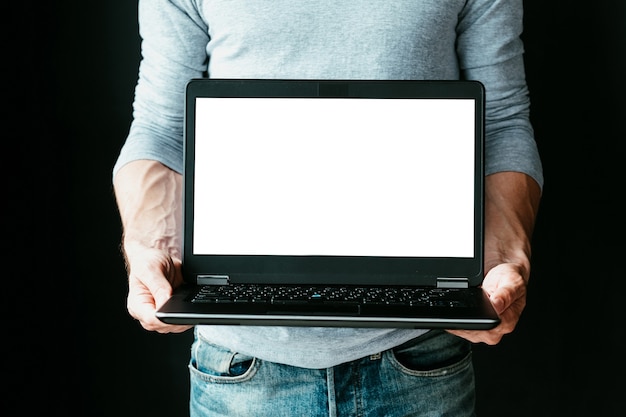 Hombre sujetando el portátil con pantalla en blanco en las manos