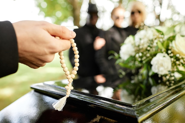 Foto hombre sujetando rosario y rezando en el funeral al aire libre