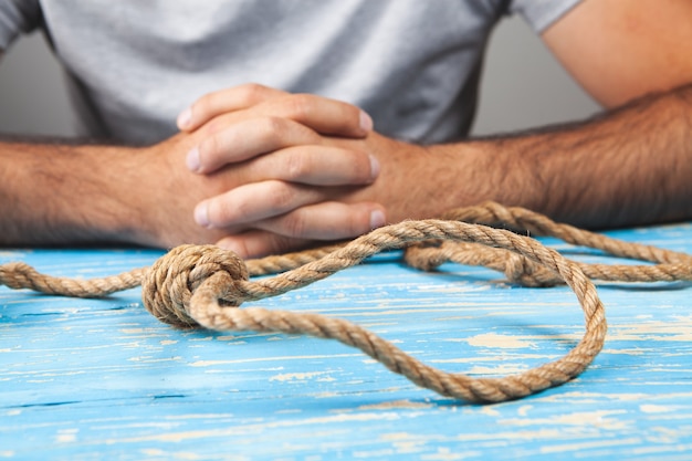 Hombre sujetando una soga. concepto de suicidio. sobre fondo gris