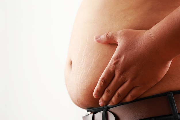 Hombre sujetando su estómago y estimando su peso, imagen conceptual de problemas de salud masculinos y obesidad