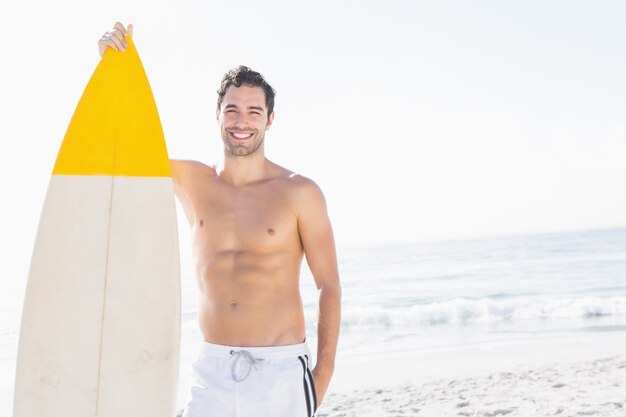 Hombre sujetando la tabla de surf en la playa