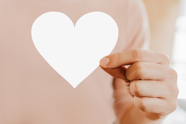 Hombre sujetando una tarjeta de amor en forma de corazón con fondo en blanco