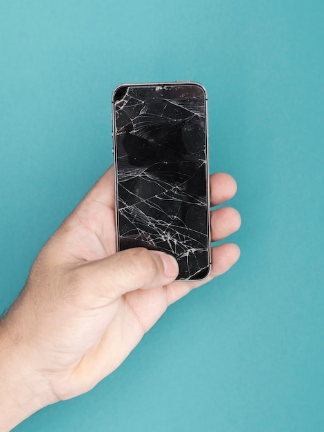 Foto hombre sujetando el teléfono con pantalla rota