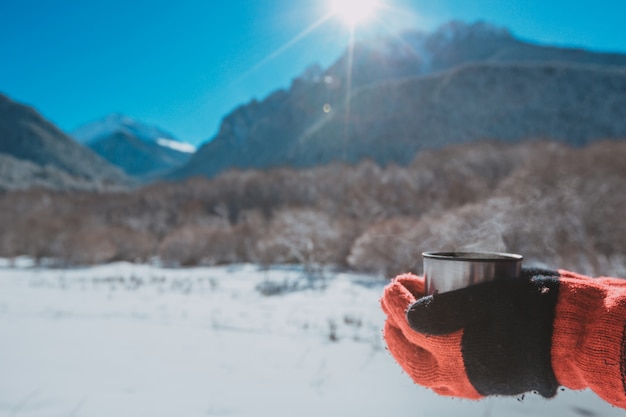 Hombre sujetando un termo en una montaña nevada