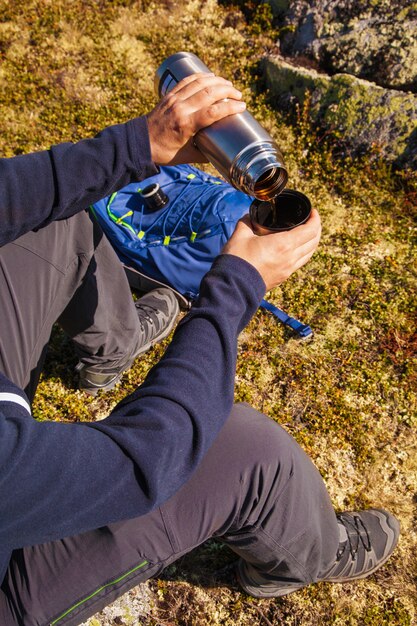 Hombre sujetando termo con té caliente al aire libre