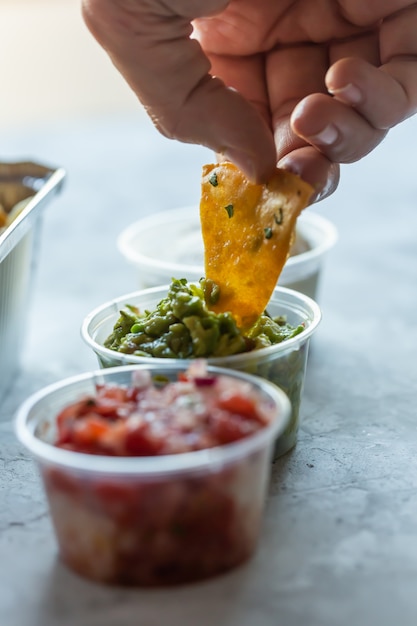 Foto un hombre sumerge nachos en salsa de guacamole verde