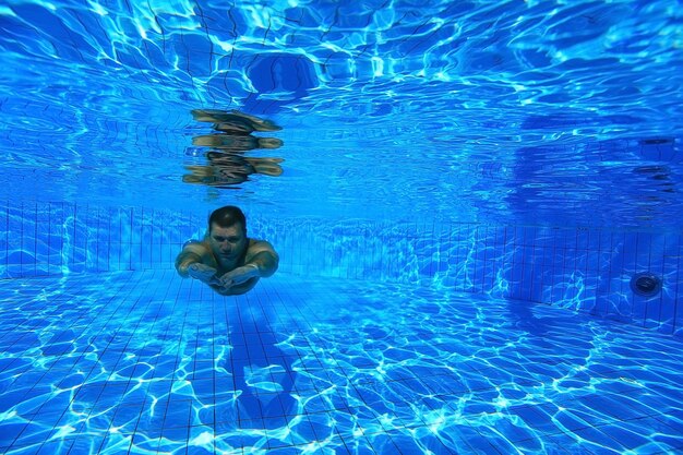 hombre se sumerge en la piscina foto submarina