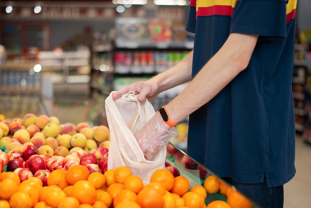 Hombre en el supermercado con bolsa ecológica tomando productos