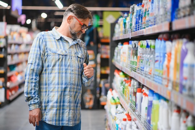 Hombre en el supermercado en el departamento de productos químicos domésticos Gran selección de productos