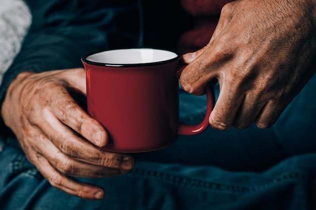 Un hombre suplica. Él sostiene una taza de papel blanco. El concepto de indigencia y pobreza.