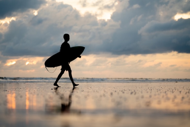 Un hombre con un surf en sus manos en la orilla del mar