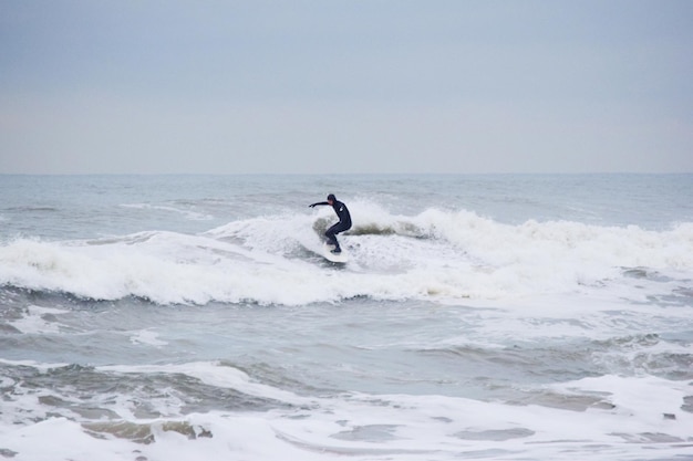 Hombre surfeando en el mar contra un cielo despejado