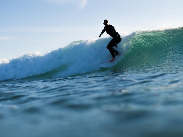 Hombre surfeando en el mar contra el cielo