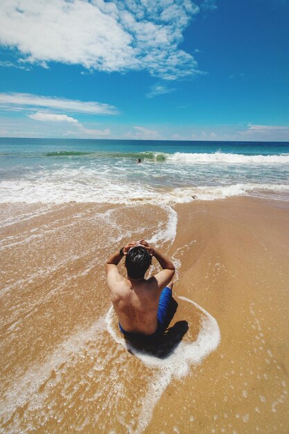 Foto hombre surfeando en la playa contra el cielo