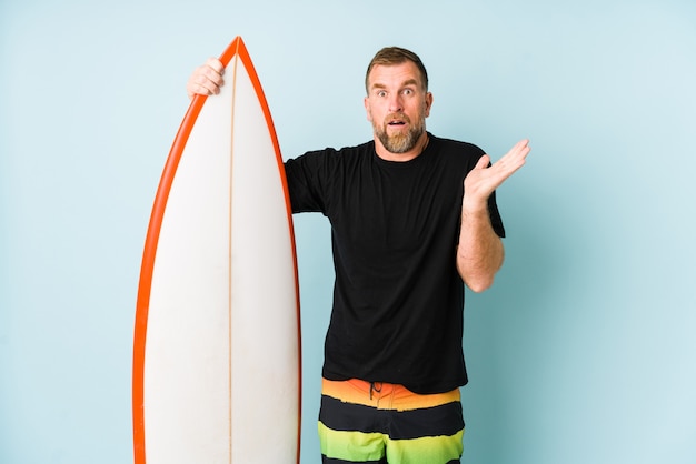 Hombre de Surfen en la pared azul sorprendido y conmocionado.