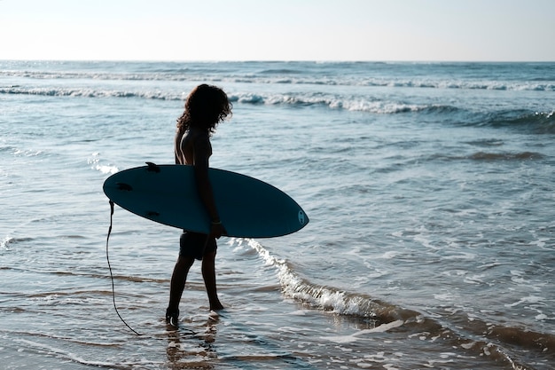 Hombre surfista sentado en la tabla de surf en la playa de arena