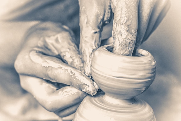 Foto un hombre con sus manos dobla una jarra de pared, que esculpe en arcilla en un círculo. crea un recipiente de arcilla. modelado de arcilla blanca, moldeando vasija. hombre caucásico haciendo buque cclay en círculo.