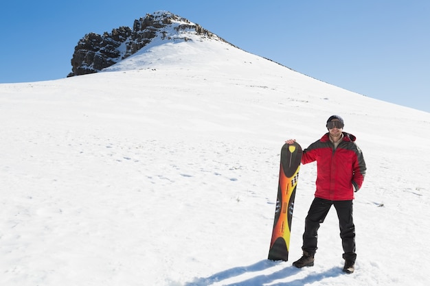 Hombre con tabla de esquí en el paisaje cubierto de nieve