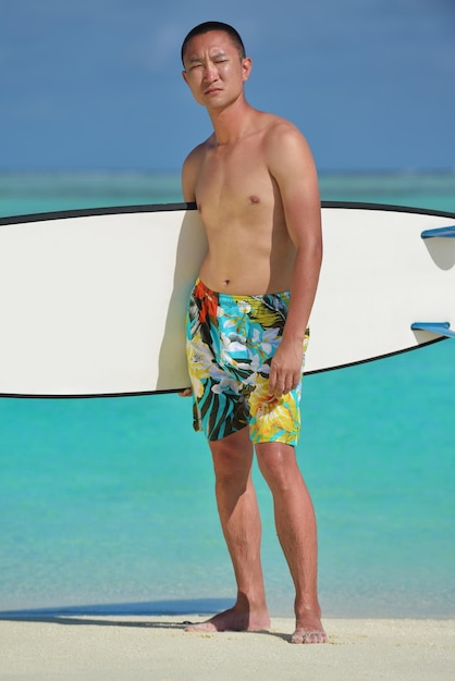 Hombre con tabla de surf en una hermosa playa tropical