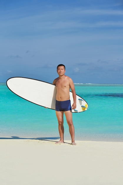 Hombre con tabla de surf en una hermosa playa tropical