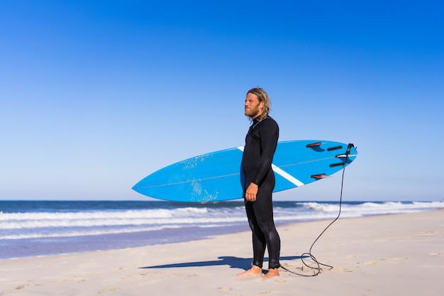 hombre con tabla de surf en la orilla del mar. Surfer en traje de baño