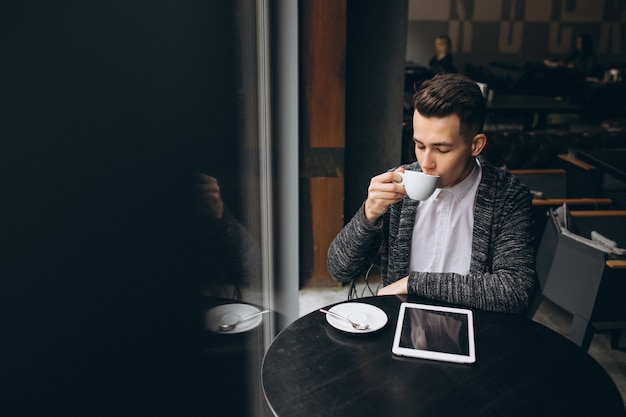 Hombre con tableta y café en una cafetería