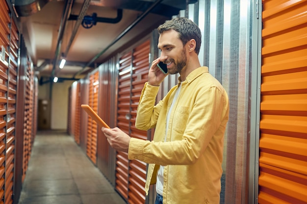 Hombre con tableta hablando por teléfono inteligente