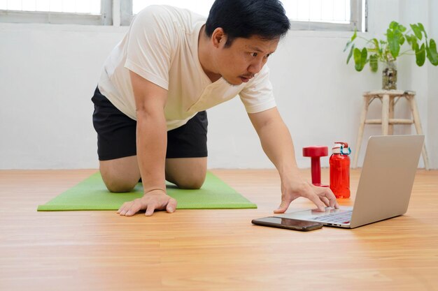 Hombre con tableta haciendo ejercicio de tablón en casa