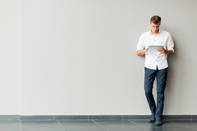 Hombre con tableta junto a la pared