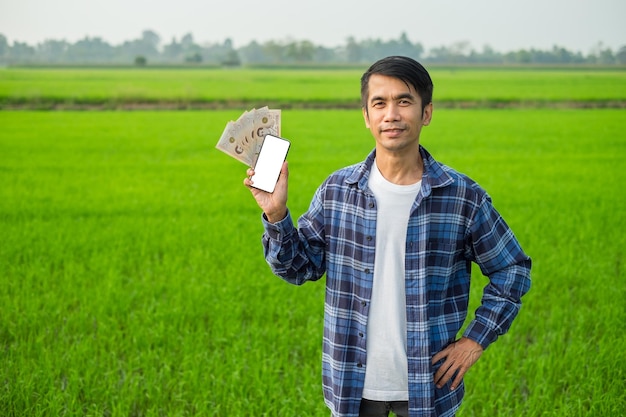El hombre tailandés Venna está de pie sosteniendo billetes y teléfono inteligente tiene una cara sonriente