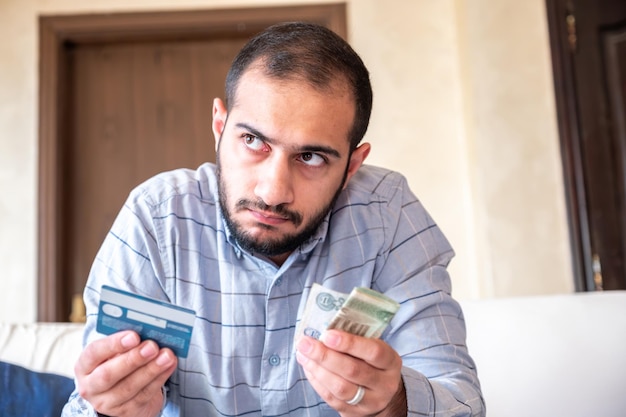 Foto hombre con una tarjeta bancaria mientras se siente estresado debido a un problema financiero