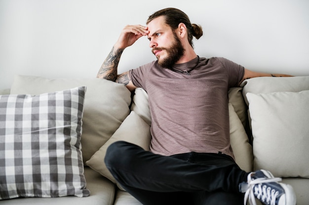 Foto hombre con tatuaje sentado en un sofá