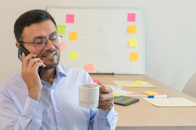 Un hombre con una taza y hablando por teléfono