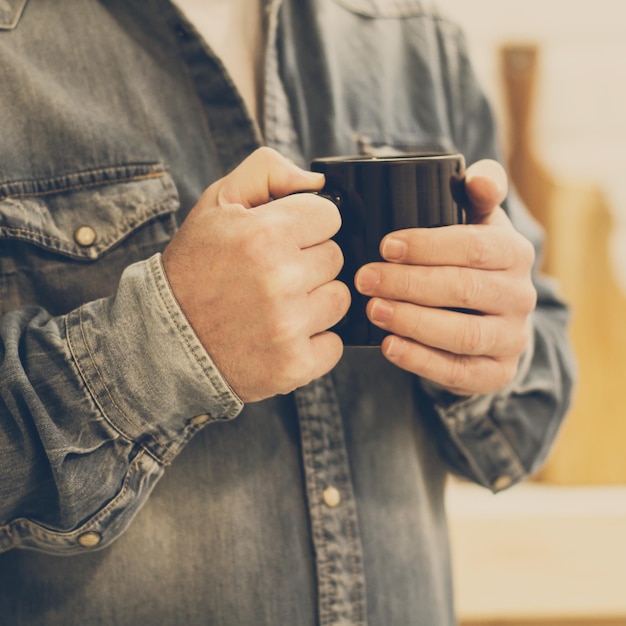 Hombre con una taza negra en la mano en una vista cercana