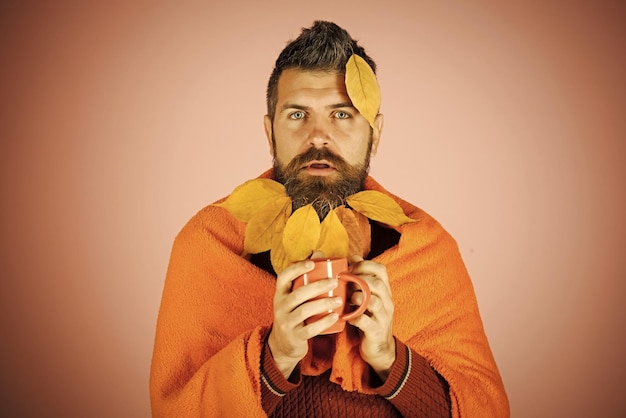 Hombre con taza de té y hojas de otoño en barba a cuadros