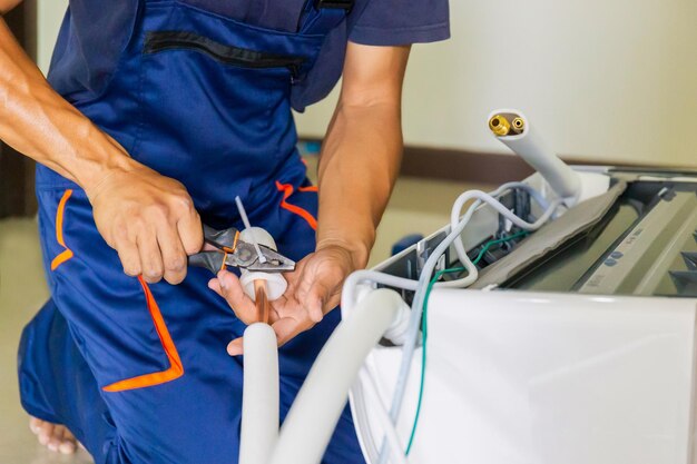 Hombre técnico instalando aire acondicionado en la casa de un cliente Joven reparador arreglando la unidad de aire acondicionado Conceptos de mantenimiento y reparación