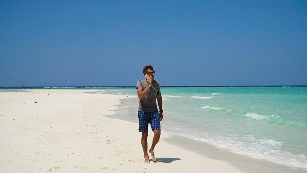 Hombre con un teléfono celular en la playa.