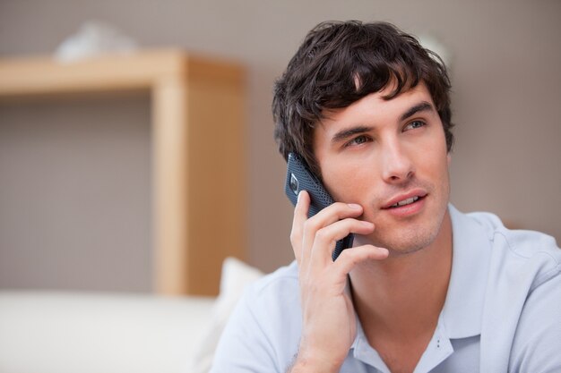 Hombre en el teléfono celular que se sienta en la sala de estar